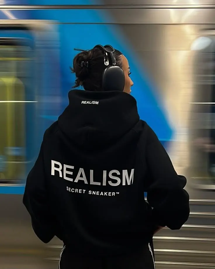 Le hoodie Realism noir, porté dans une gare